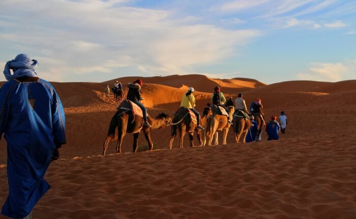 Children riding camels in the golden Sahara Desert during Morocco family holiday package morocco