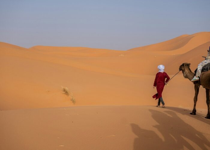 A man riding on the back of a camel in the desert